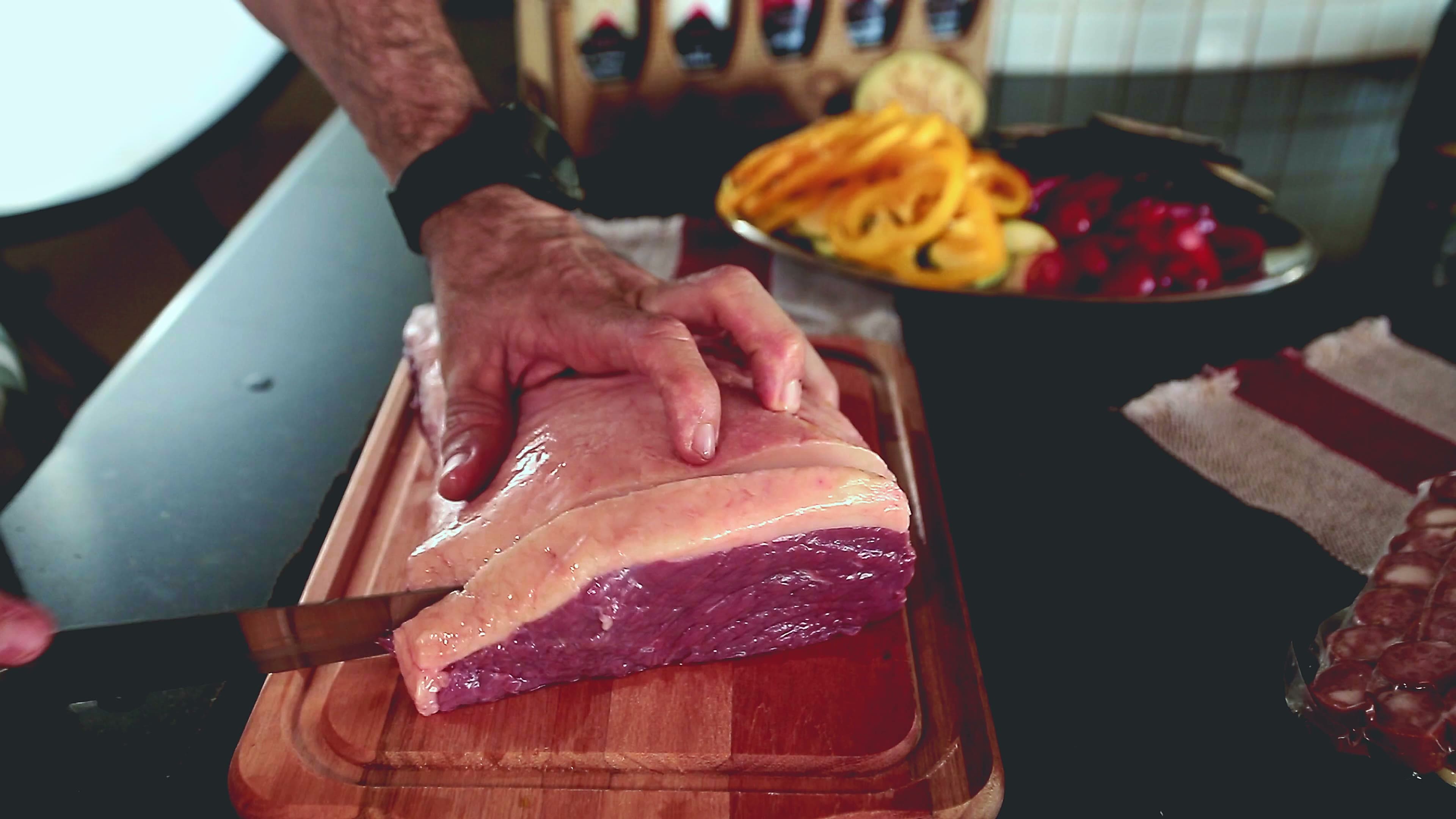 A butcher slicing a roast on a board