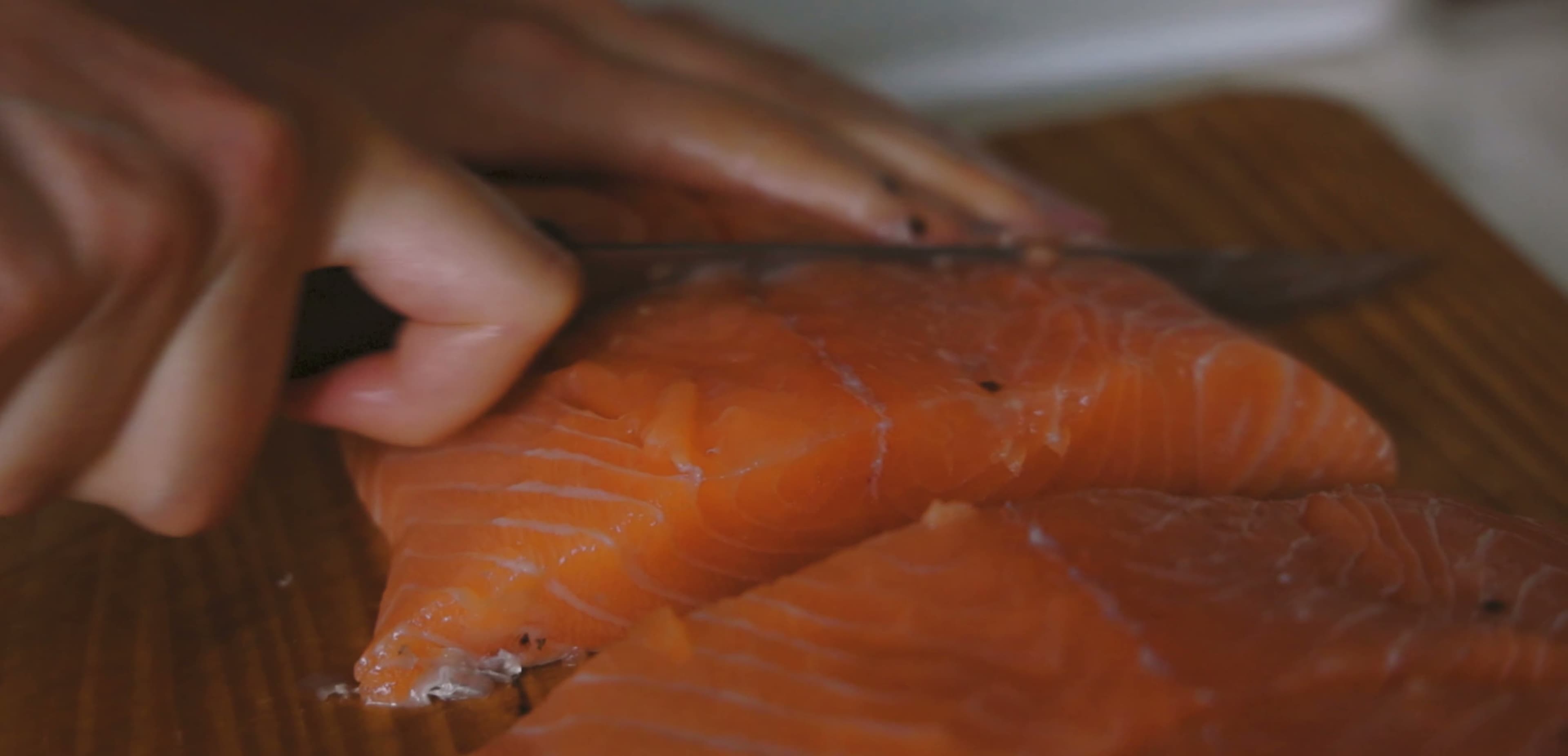 Hands portioning a salmon fillet