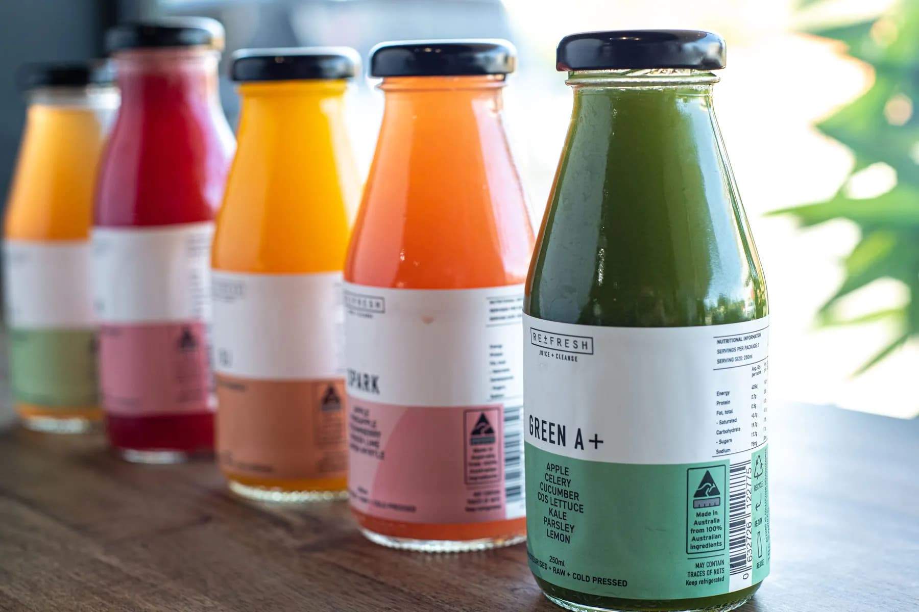 Bottles of orange, pink, and green juice in a row